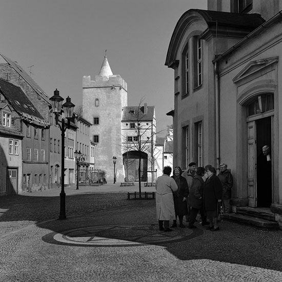 Vor der Marienkirche in Naumburg nach dem sonntäglichen Gottesdienst. Am anderen Ende
des Platzes das Marientor. Die Familie Nietzsche wohnte hinter der Kirche im Haus
Marienmauer 623 [jetzt 2] von April 1856 bis Oktober 1858. In unmittelbarer
Nachbarschaft befanden sich Kaserne und Exerzierplatz der Feldartillerie,
Stadtgefängnis, Gerichtsgefängnis, Armenhaus, Armenschule und Waisenhaus.

Thomas Steinert
1990/99, Piezo-Pigment-Print, 40 x 40 cm, Ed. 7 


